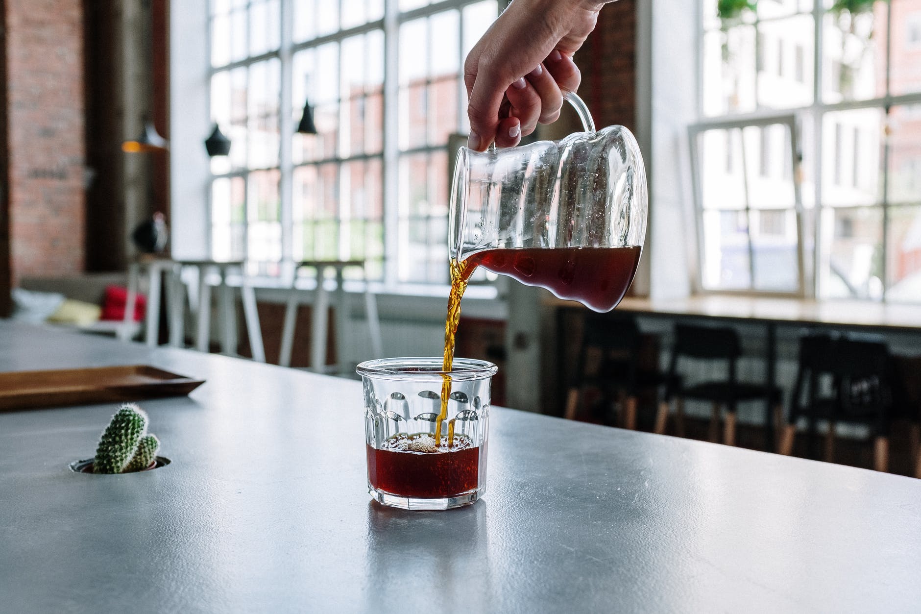 person pouring red liquid on clear drinking glass